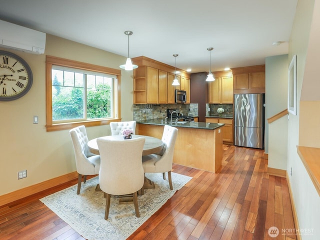 dining area featuring an AC wall unit, baseboards, and light wood-style floors