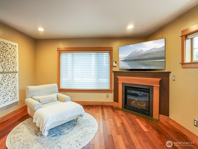 sitting room featuring recessed lighting, baseboards, a fireplace with flush hearth, and wood finished floors