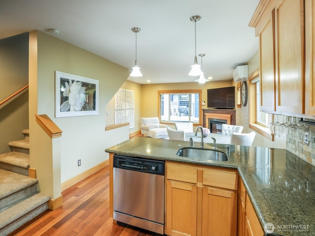 kitchen featuring wood finished floors, dishwasher, a sink, a peninsula, and open floor plan