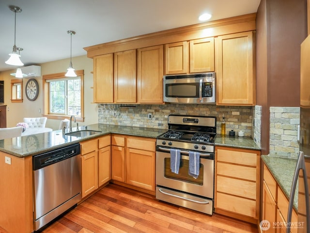 kitchen with dark stone counters, tasteful backsplash, a sink, light wood-style flooring, and stainless steel appliances