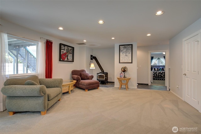 living area with light colored carpet, visible vents, recessed lighting, and a wood stove