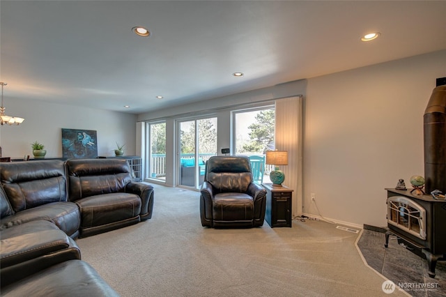 carpeted living room with a wood stove, visible vents, a chandelier, baseboards, and recessed lighting