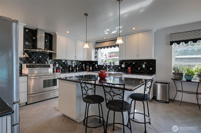 kitchen featuring dark countertops, stainless steel appliances, white cabinets, and wall chimney exhaust hood