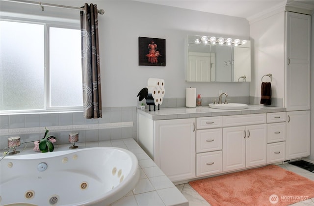 full bath featuring a tub with jets, vanity, and a healthy amount of sunlight