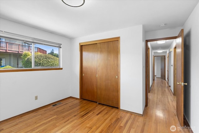 unfurnished bedroom with a closet, light wood-type flooring, and visible vents