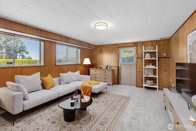 living room featuring wooden walls, visible vents, and light carpet
