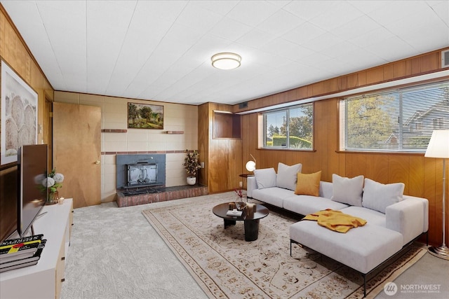 carpeted living room with visible vents and wood walls