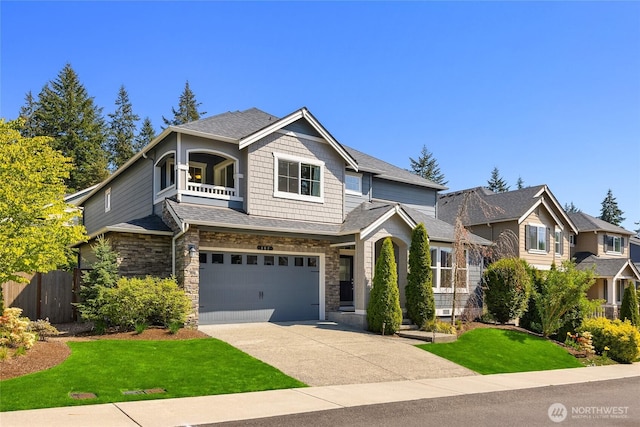 craftsman-style home with fence, a balcony, a front lawn, concrete driveway, and an attached garage