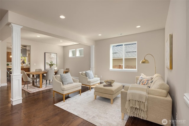 living room featuring recessed lighting, baseboards, ornate columns, and dark wood-style floors