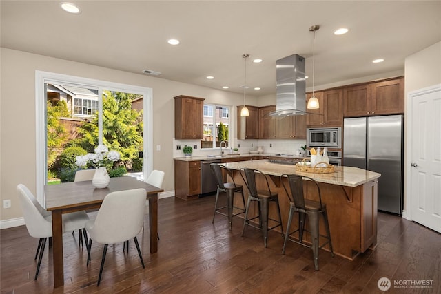 kitchen with appliances with stainless steel finishes, a sink, a center island, island range hood, and dark wood-style floors