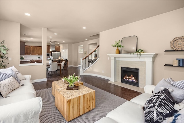 living room featuring stairs, recessed lighting, a fireplace with flush hearth, and dark wood-type flooring