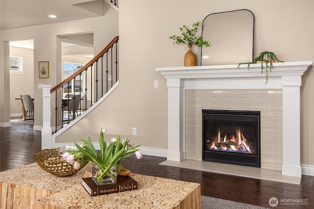 details with a tiled fireplace, baseboards, and wood finished floors
