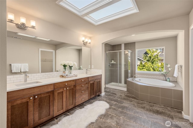 bathroom with a skylight, a sink, a garden tub, and a stall shower