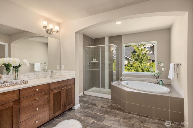 full bathroom featuring a sink, double vanity, a shower stall, and a bath