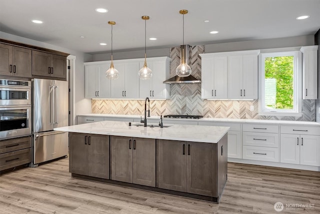 1343 211th Ave NE, Sammamish, WA 98074 - kitchen with stainless steel appliances, wall chimney range hood, white cabinetry, an island with sink, and backsplash