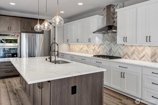 1343 211th Ave NE, Sammamish, WA 98074 - kitchen featuring wall chimney exhaust hood, appliances with stainless steel finishes, light wood finished floors, recessed lighting, and an island with sink