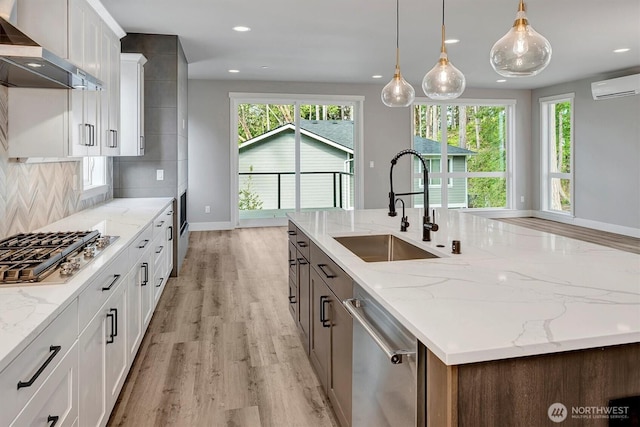 1343 211th Ave NE, Sammamish, WA 98074 - kitchen with wall chimney range hood, stainless steel appliances, a wall mounted AC, light wood-type flooring, and a center island with sink