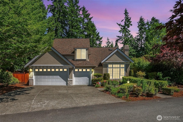 16639 Northup Way, Bellevue, WA 98008 - traditional home featuring a garage, stone siding, stucco siding, concrete driveway, and a chimney