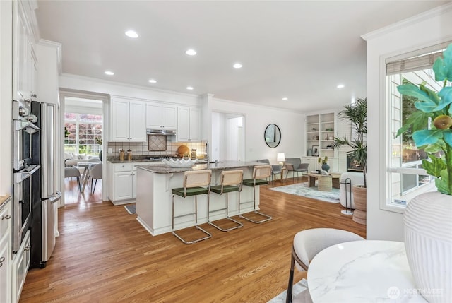 16639 Northup Way, Bellevue, WA 98008 - kitchen featuring ornamental molding, a kitchen bar, light wood-type flooring, white cabinets, and a center island