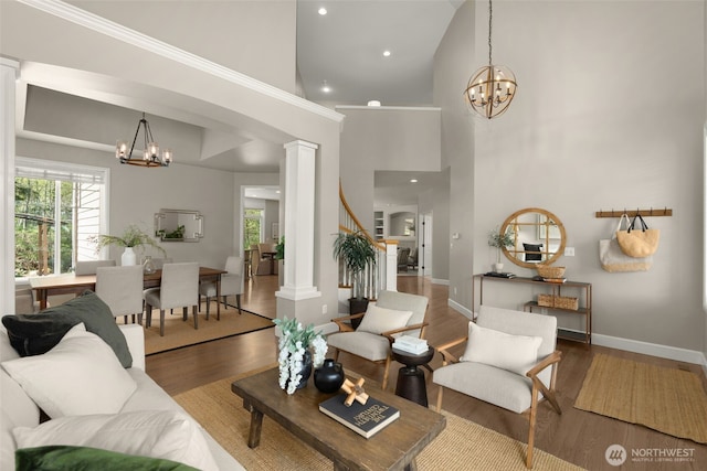 living area with ornate columns, wood finished floors, and a chandelier