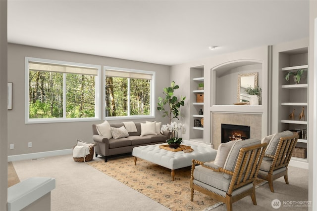 carpeted living area with built in features, baseboards, and a tile fireplace