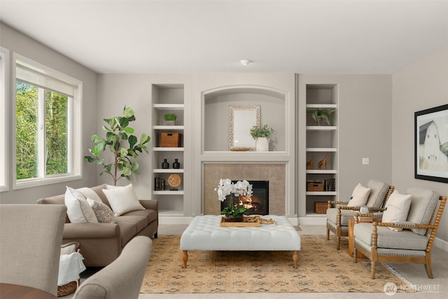 carpeted living area featuring baseboards, built in features, a healthy amount of sunlight, and a fireplace
