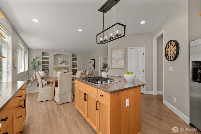 kitchen with appliances with stainless steel finishes, a center island, baseboards, light wood finished floors, and open floor plan
