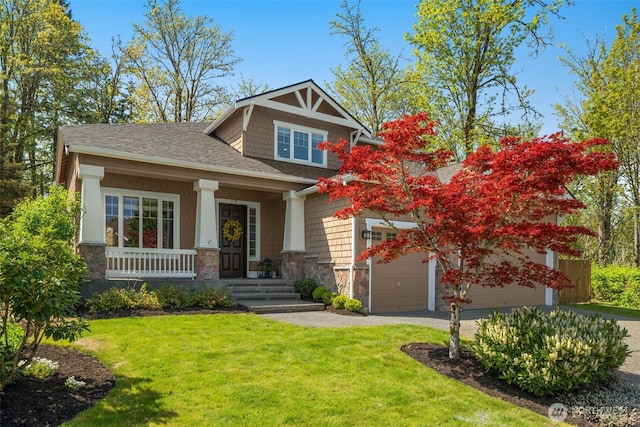 craftsman-style house featuring a front lawn, stone siding, roof with shingles, a porch, and driveway