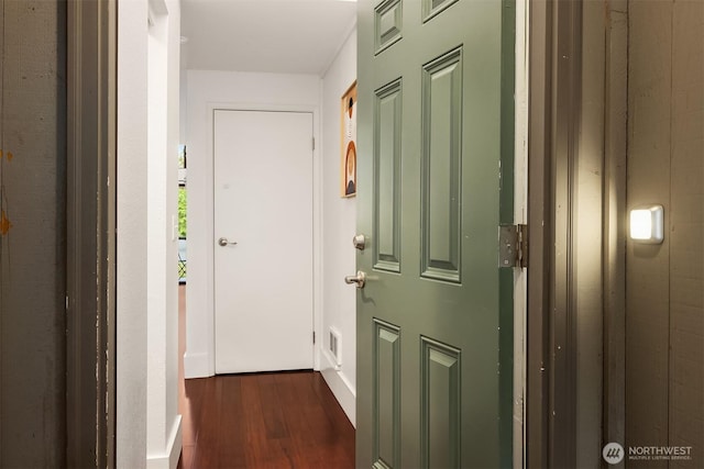corridor featuring dark wood finished floors and baseboards