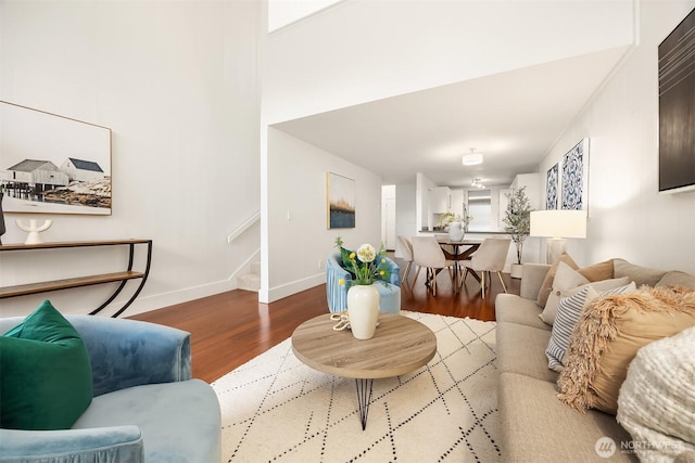 living room featuring stairs, wood finished floors, and baseboards