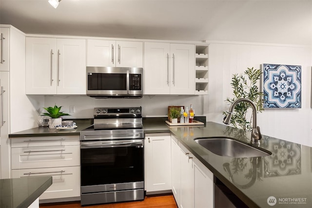 kitchen with stainless steel appliances, a sink, and dark countertops