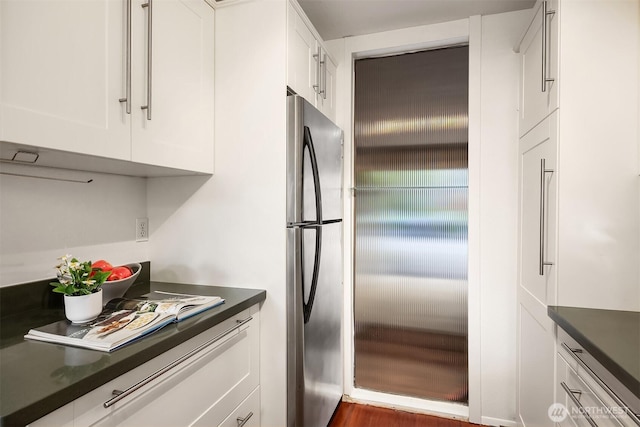 kitchen featuring freestanding refrigerator, dark countertops, and white cabinetry