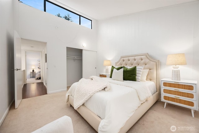carpeted bedroom featuring a closet, baseboards, and a high ceiling