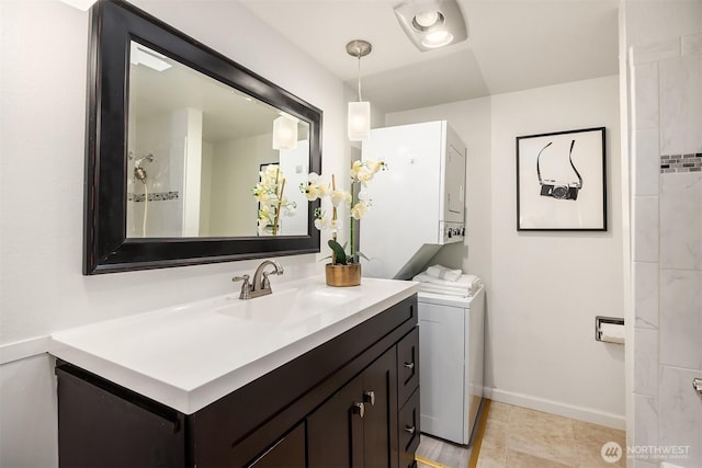 bathroom featuring estacked washer and dryer, baseboards, vanity, and tile patterned floors