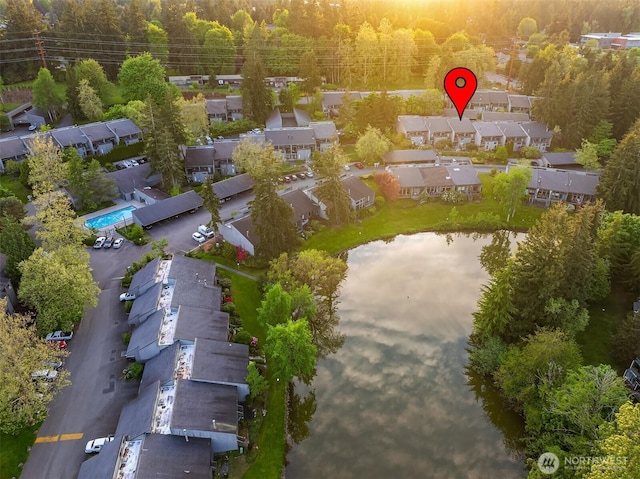 drone / aerial view of a nearby body of water and a forest