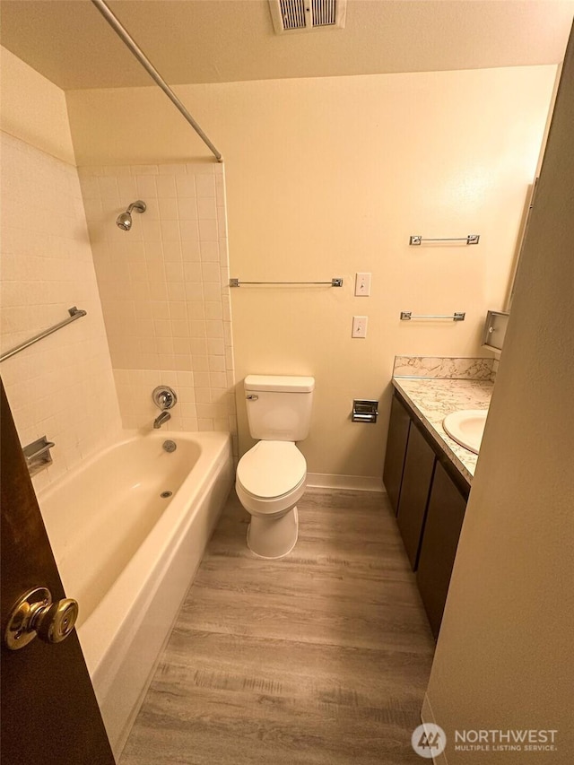 full bath with visible vents, tub / shower combination, toilet, wood finished floors, and vanity