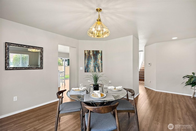dining space featuring baseboards, stairs, wood finished floors, and a notable chandelier