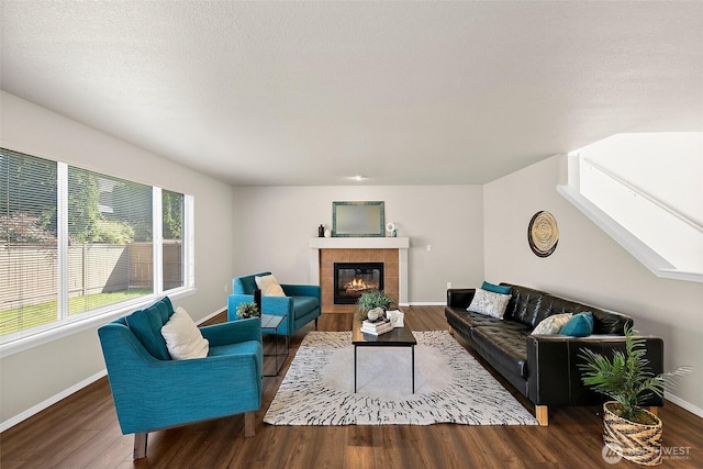 living area featuring baseboards, wood finished floors, and a tile fireplace