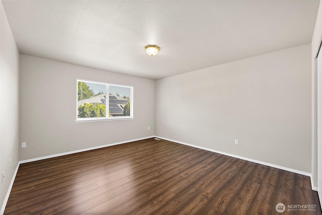 unfurnished room with baseboards, dark wood finished floors, and a textured ceiling