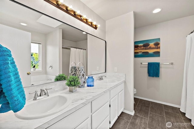 bathroom with baseboards, double vanity, toilet, and a sink