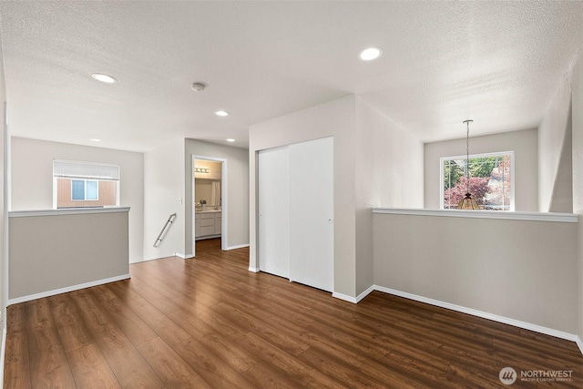 spare room featuring baseboards, a textured ceiling, and wood finished floors
