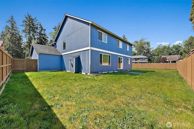 back of property with a yard and a fenced backyard