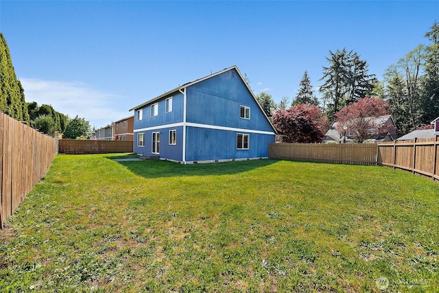 rear view of property with a fenced backyard and a yard