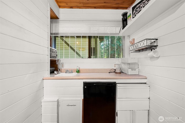 bar featuring wooden walls, fridge, and a sink