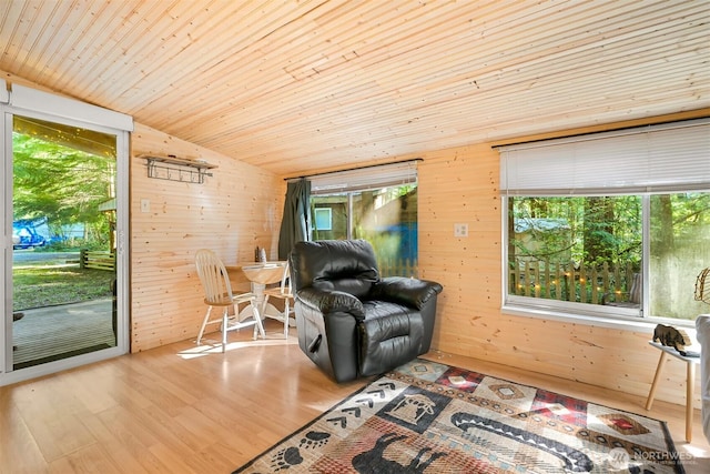 sitting room with wooden walls, wooden ceiling, a healthy amount of sunlight, and lofted ceiling