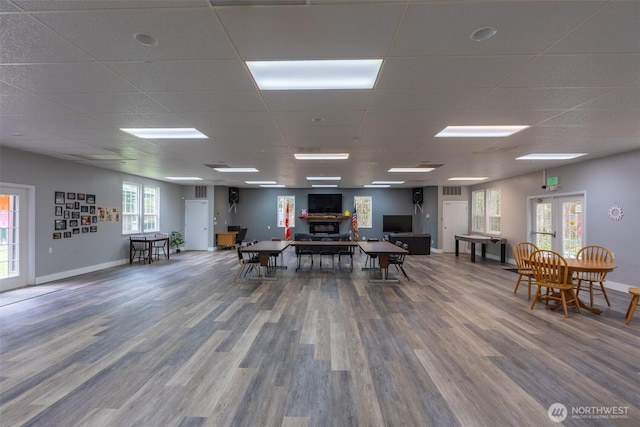 interior space featuring baseboards, a paneled ceiling, wood finished floors, and a fireplace