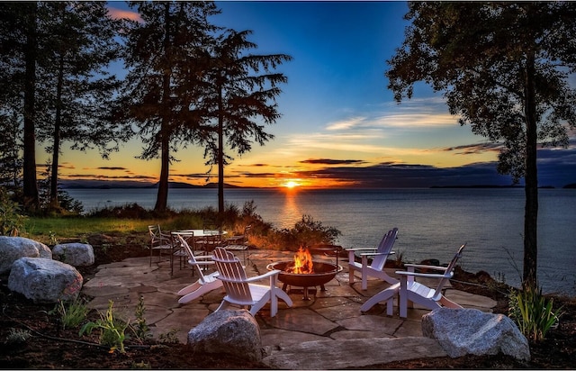 patio terrace at dusk with an outdoor fire pit and a water view