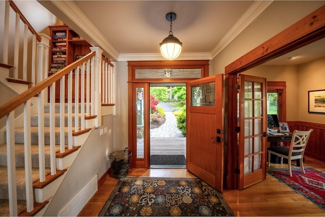 foyer featuring ornamental molding, visible vents, stairway, and wood finished floors