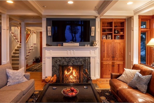living room with beamed ceiling, stairway, wood finished floors, ornamental molding, and a high end fireplace