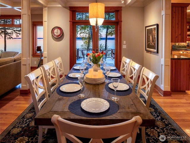 dining room with baseboards, ornamental molding, and light wood finished floors